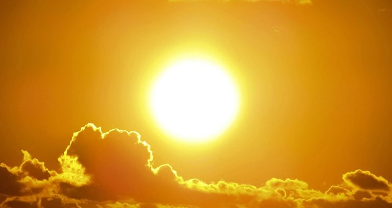 Jarko sunce iznad tamnih oblaka na narandžastom nebu