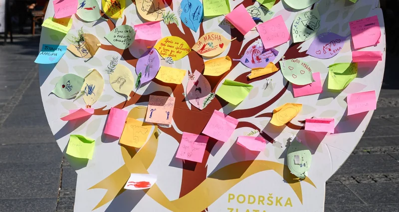 Instalacija NURDOR-a u obliku drveta, prekrivena raznobojnim porukama podrške, sa natpisom „Podrška zlata vredna“.